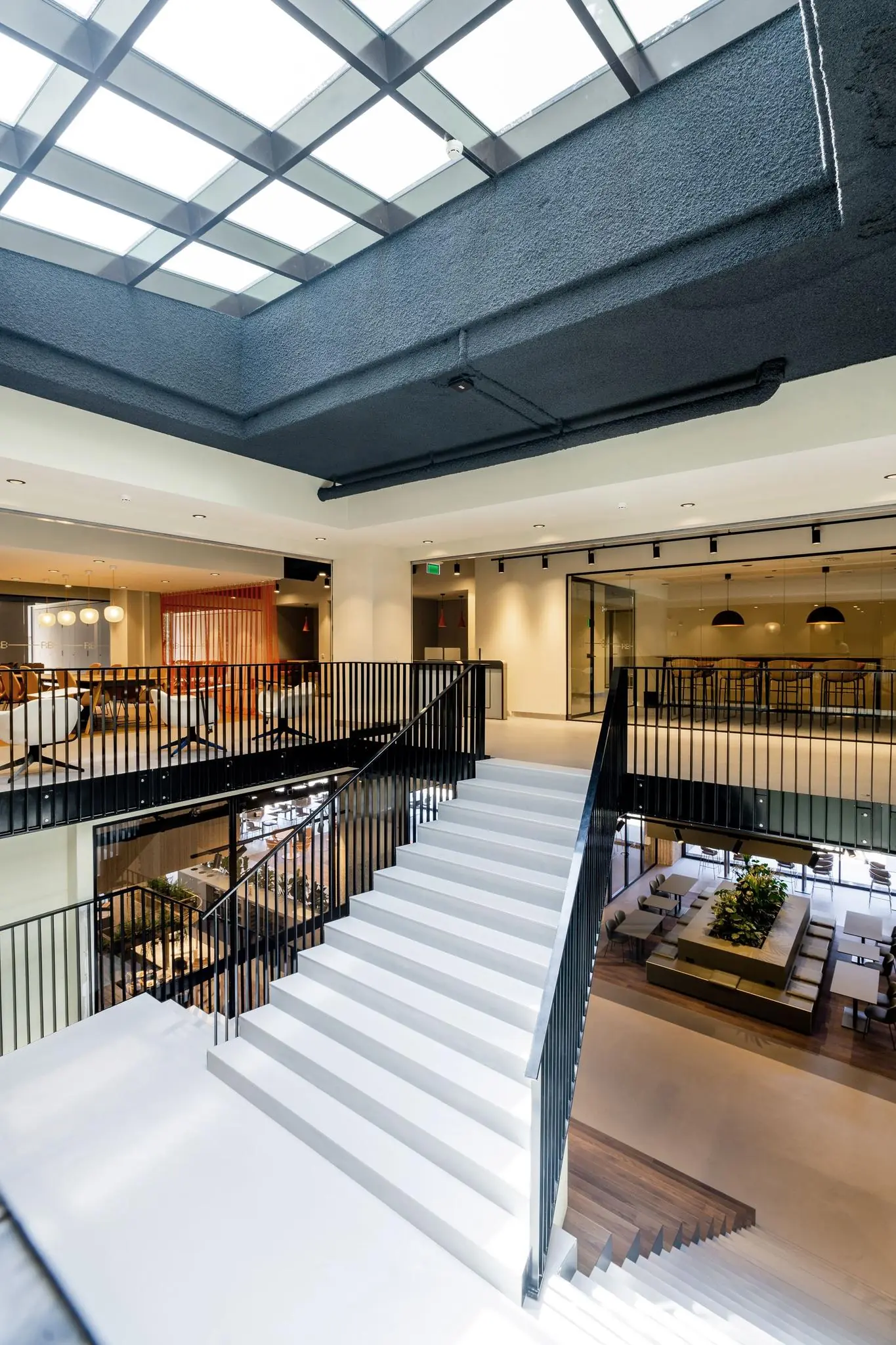 Moderne open kantoorruimte aan de Aert van Nesstraat met een grote witte trap en glazen dak.